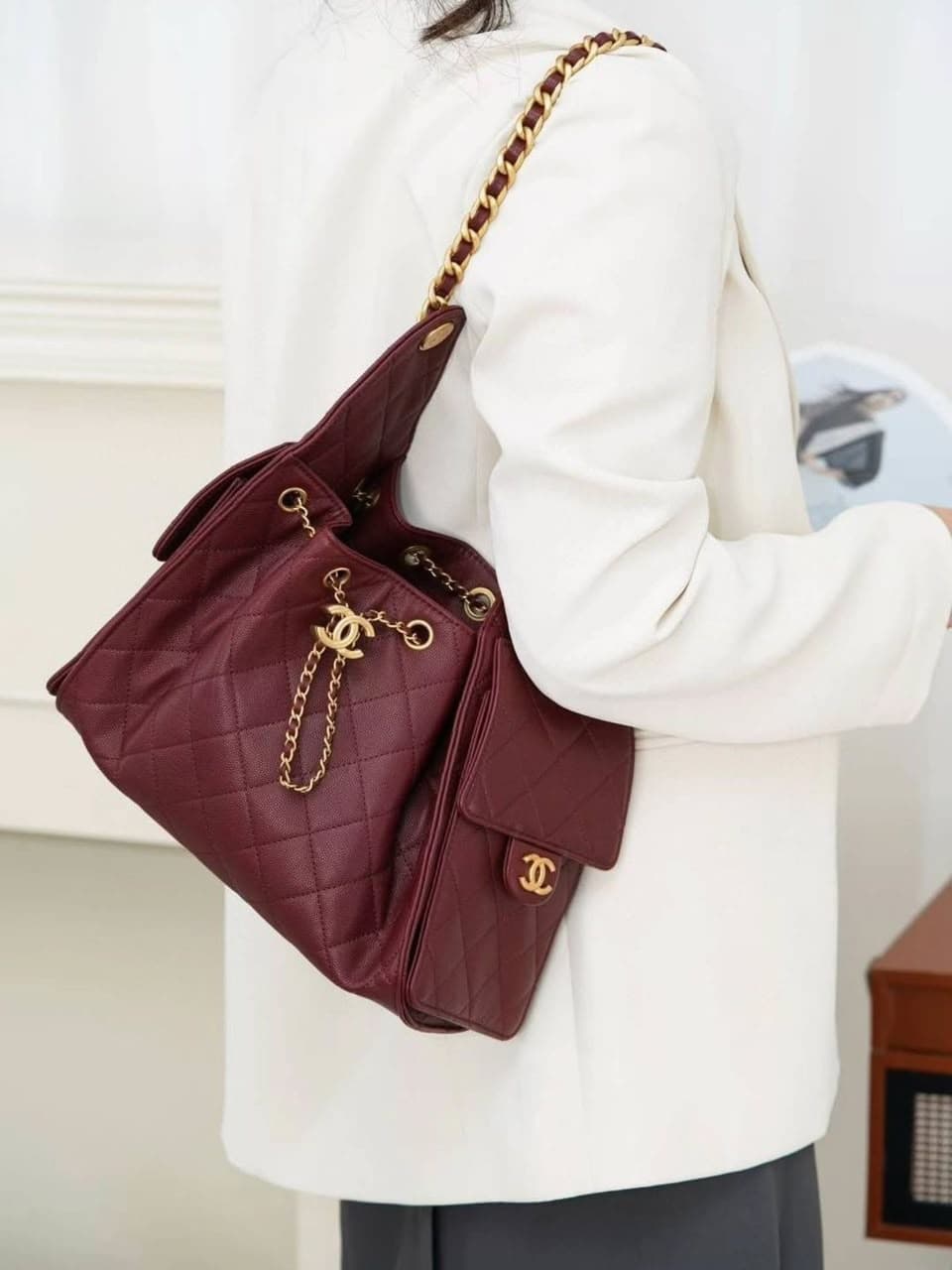 Burgundy quilted leather backpack with gold hardware on white blazer