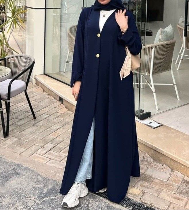 Model wearing navy blue abaya coat with gold buttons and white sneakers